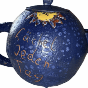 Dunkelblaue Teekanne von Omega-Sun. Sonne Oben, "Lächel Jeden Tag" steht auf der Kanne